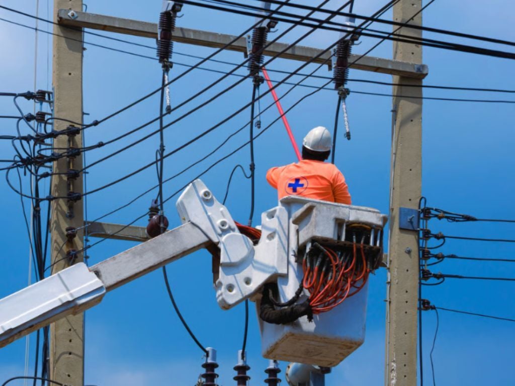 Operario en un hidroelevador que aplica protocolos de seguridad eléctrica para intervenir redes de alta tensión en altura.