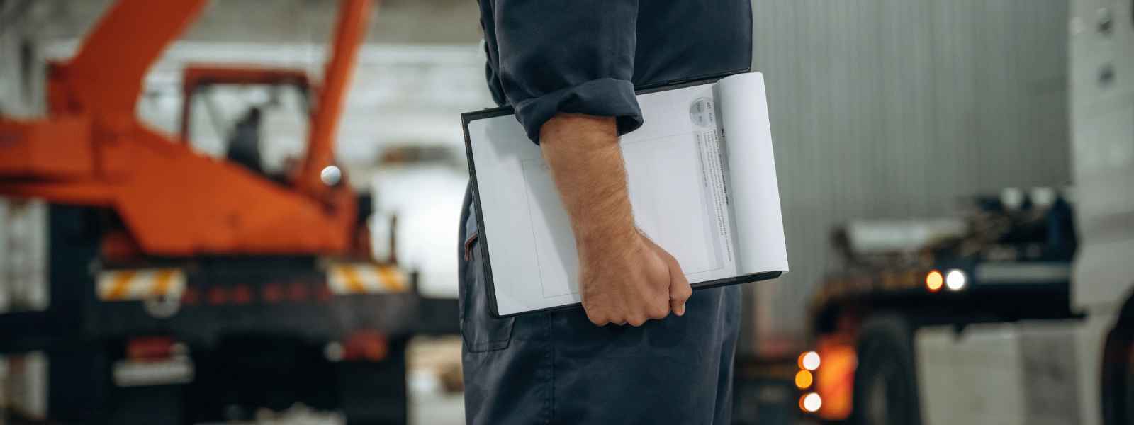 Trabajador revisando una ficha técnica de grúas en una faena industrial.